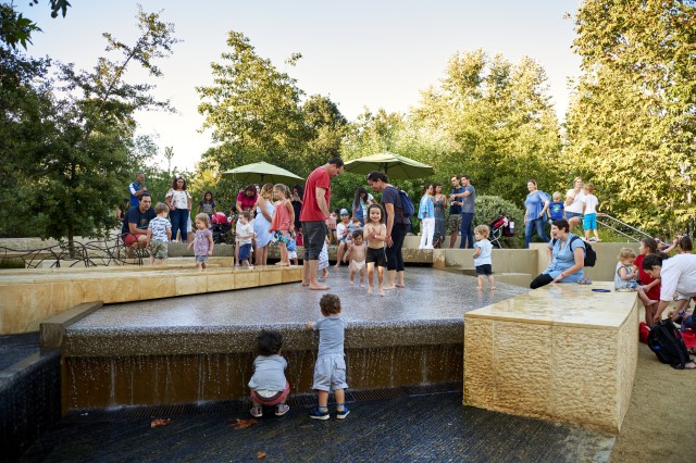 kids playing in urban waterfall in the nature gardens