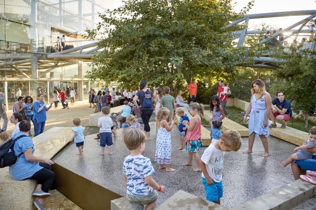 Kids flock to wade in the urban waterfall on a hot summer day