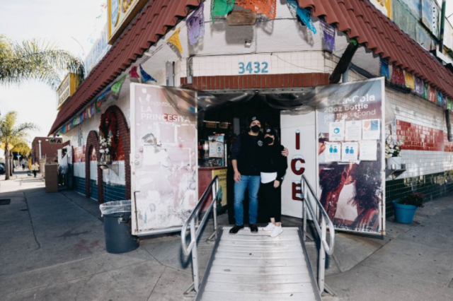 two people pose in front of storefront 