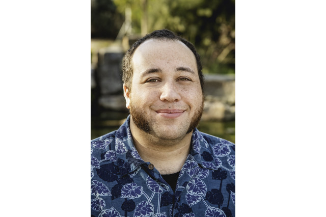 Head and shoulders portrait of Tony Turner, smiling and wearing a blue shirt with a pattern of leaves