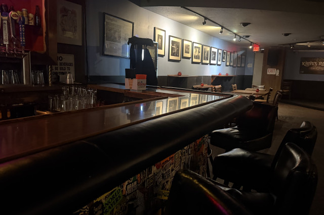 Dark, wood-paneled bat with photos of rockstars on the wall and small stage in the background.