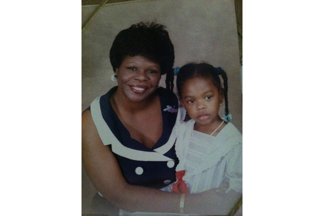 A Woman poses for a portrait with her young daughter on her lap.