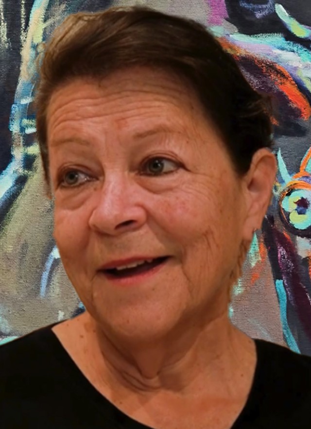 Head and shoulders portrait of Barbara Carrasco in front of colorful mural