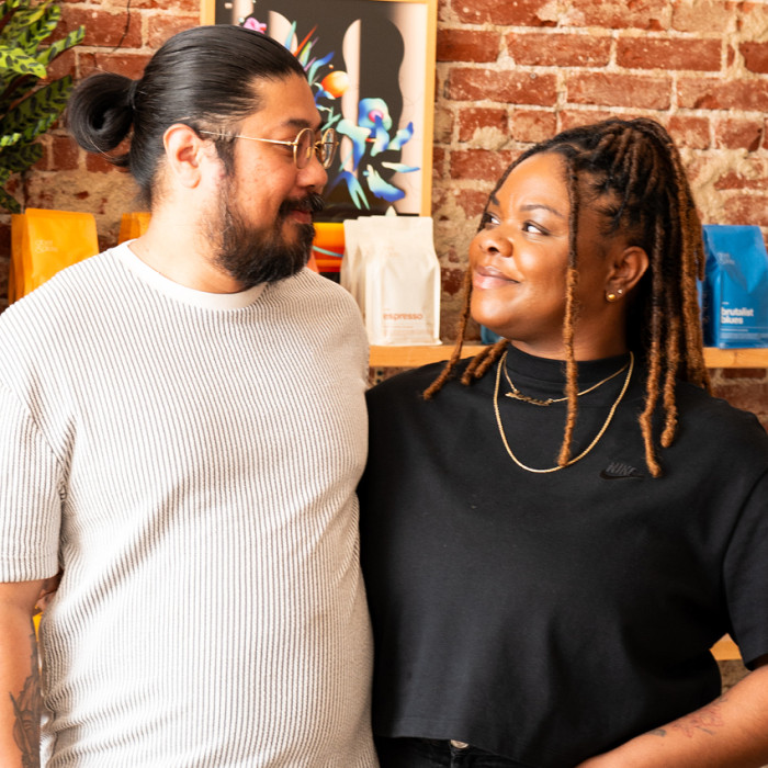 A man and woman stand in their 70's style coffee shop.