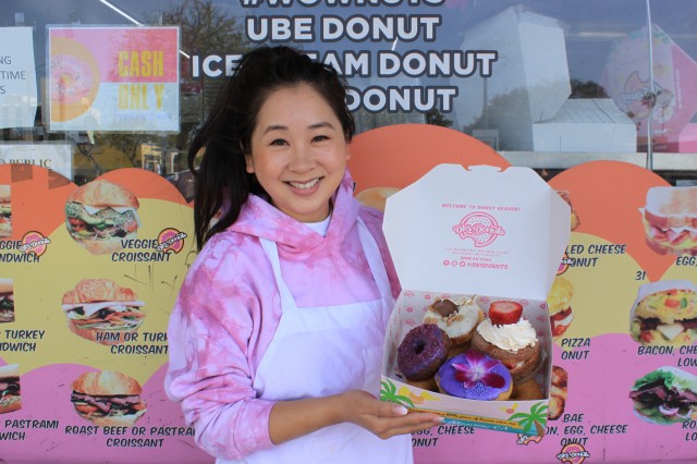 Woman standing holding box of donuts