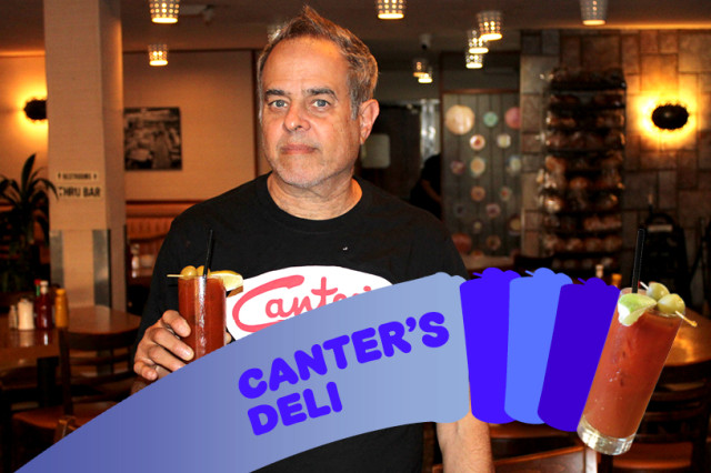 Man in black t-shirt with Canter's Deli logo on it, standing inside a restaurant holding a bloody mary drink and Canter's branded napkin.