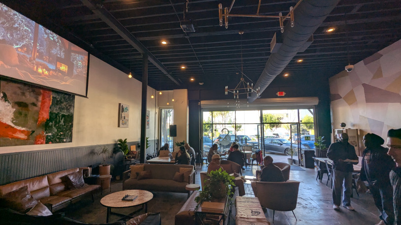 A coffee shop interior shows a welcoming space as customers take up space on the couches, at the tables and at the counter.
