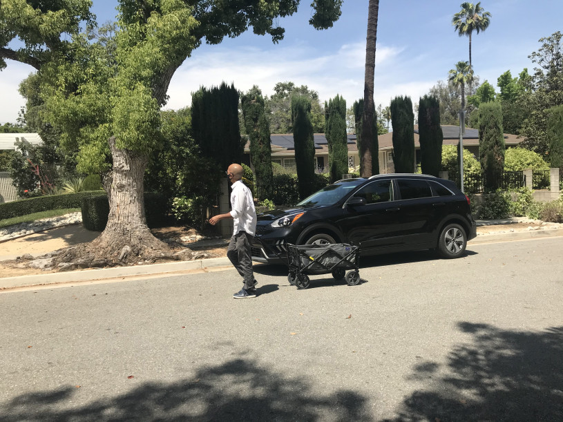 Man in a medical face mask carrying a wagon down the street to make deliveries during the Covid Pandemic.