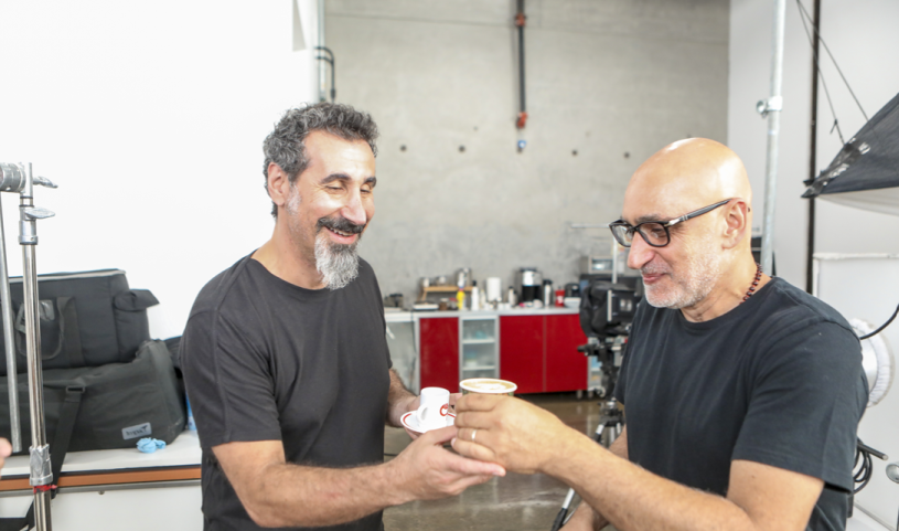 Two Armenian men in dark t-shirts celebrate drinking coffee