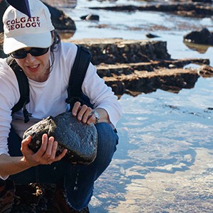 Jann Vendetti crouching in the water holding abalone